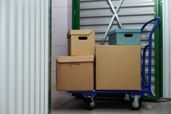 Stacked,Cardboard,Boxes,And,Storage,Containers,Sitting,On,Blue,Metal